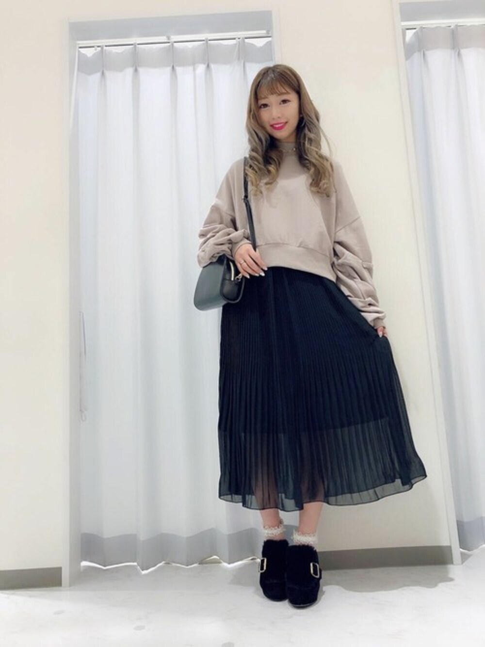 ベージュ系のTシャツ/カットソー、ブラック系のスカート、ブラック系のショルダーバッグを着用したレディースの冬コーディネートの1枚目の写真