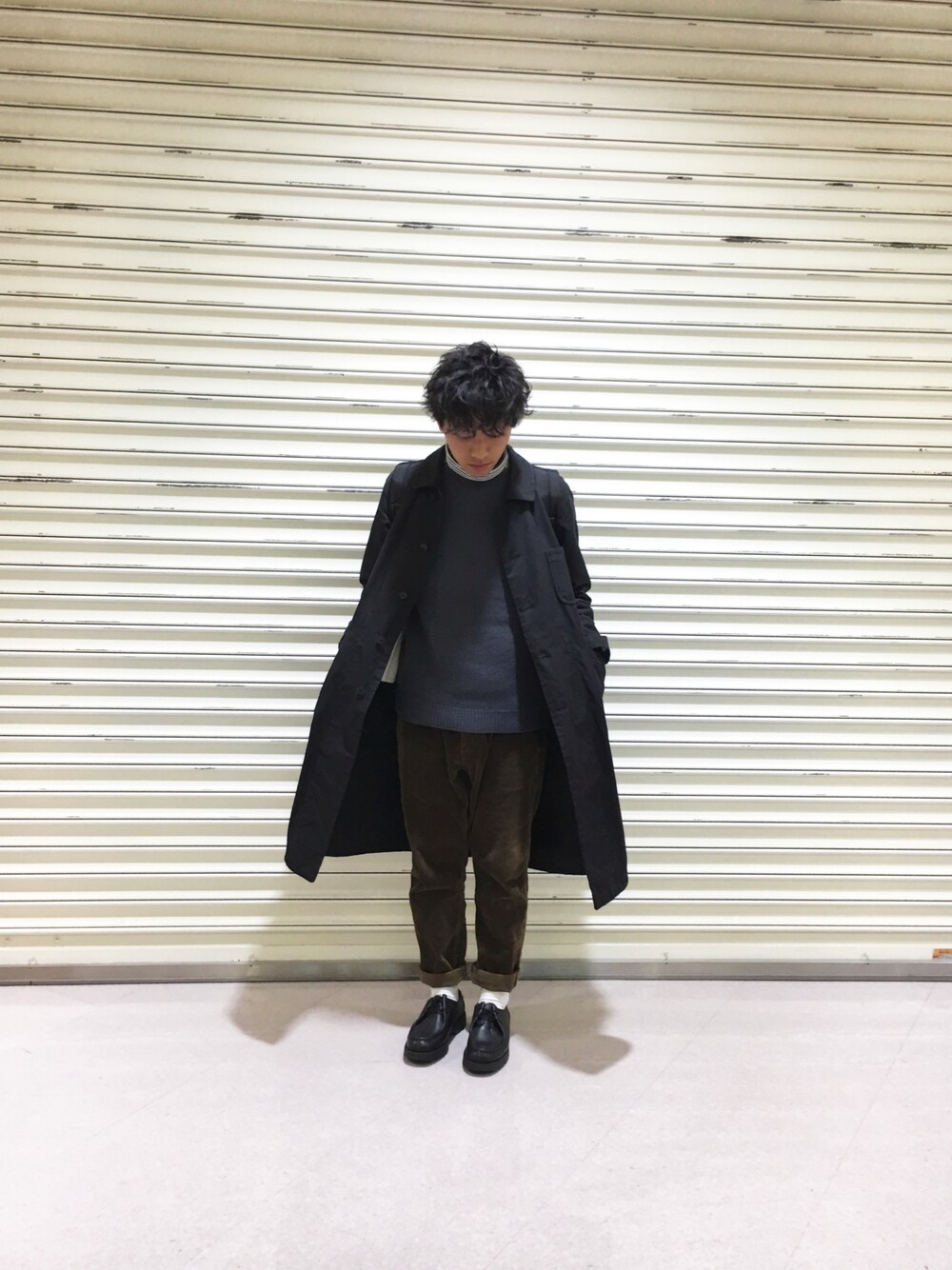 ブルー系のステンカラーコート、ブルー系のニット/セーター、ブラック系のTシャツ/カットソーを着用したメンズの秋コーディネートの1枚目の写真