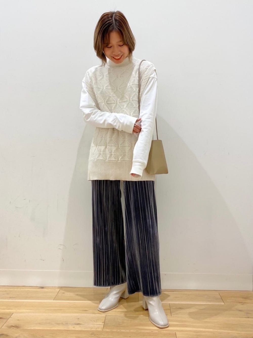 ホワイト系のベスト、ホワイト系のTシャツ/カットソー、ベージュ系のショルダーバッグを着用したレディースの冬コーディネートの1枚目の写真