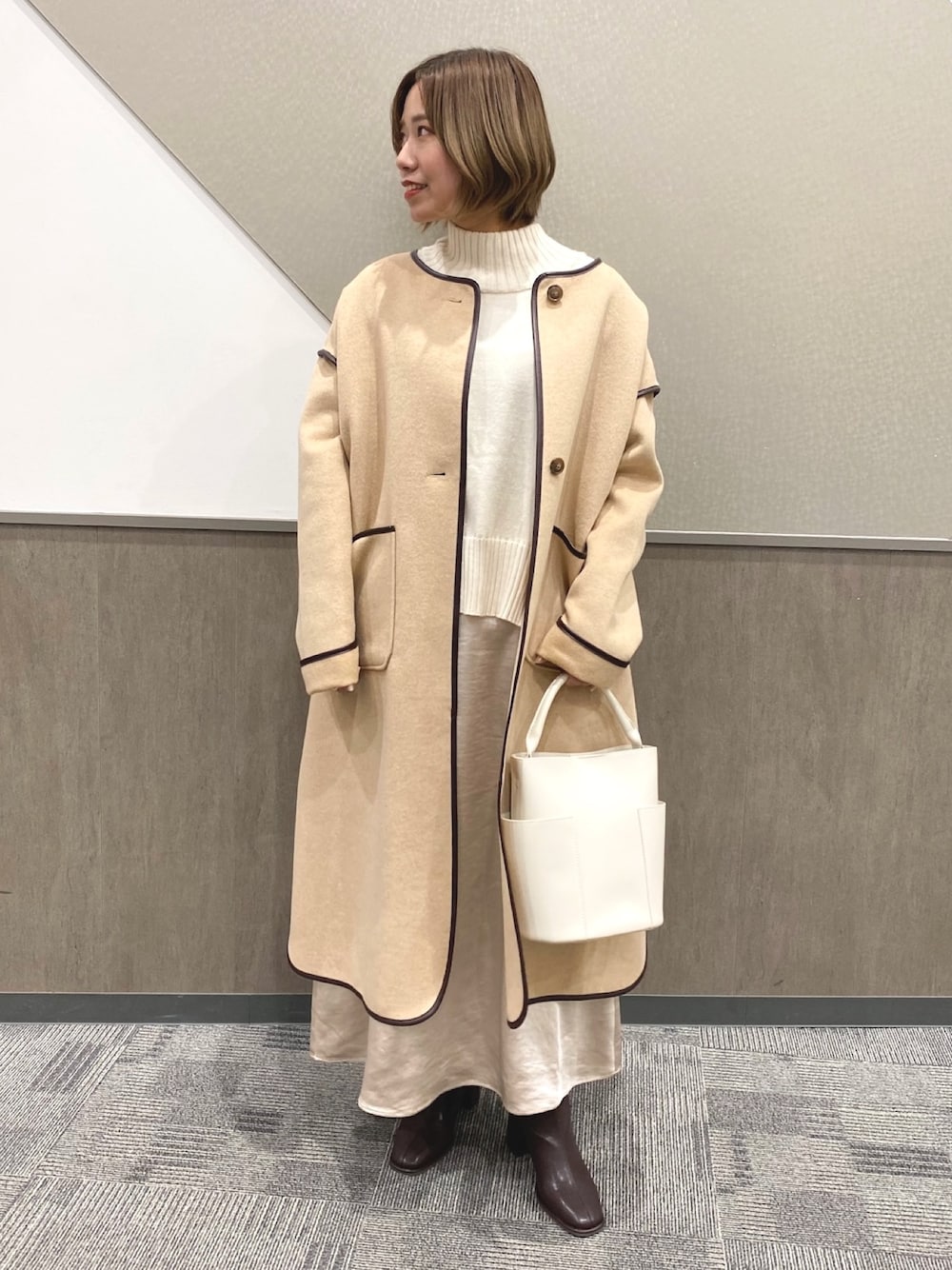 ホワイト系のニット/セーター、ベージュ系のノーカラージャケット、ホワイト系のバッグを着用したレディースの冬コーディネートの1枚目の写真