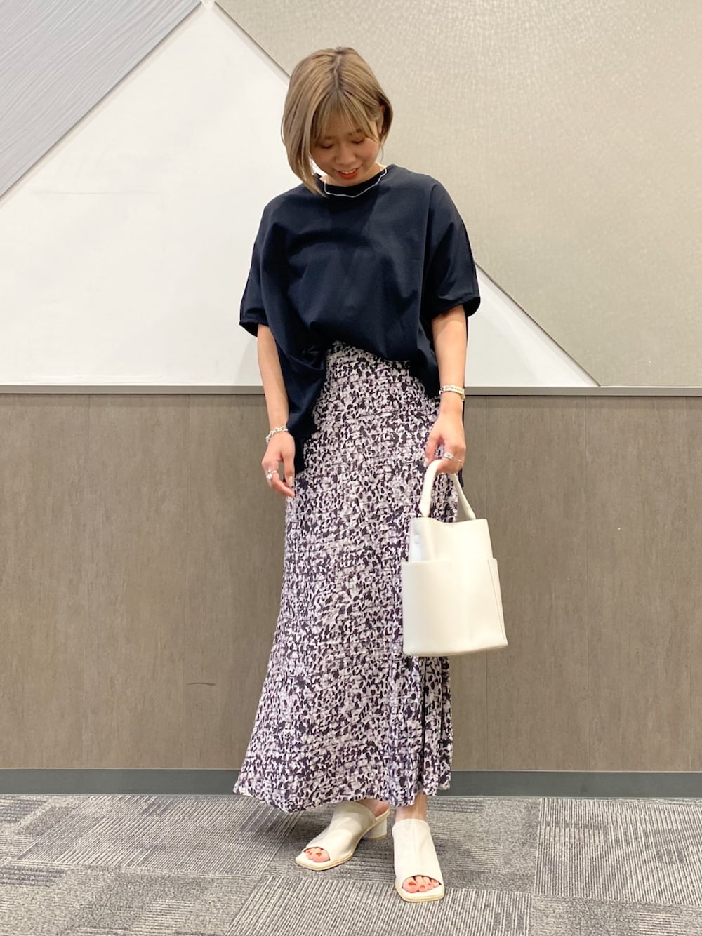 ブラック系のTシャツ/カットソー、グレー系のスカート、ホワイト系のサンダルを着用したレディースの春コーディネートの1枚目の写真