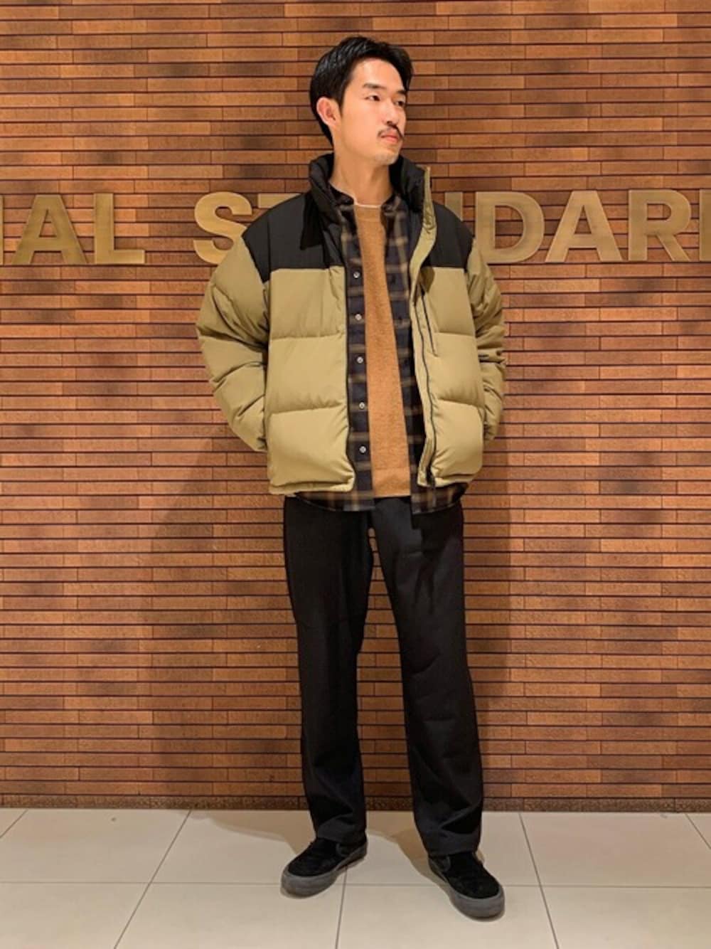 グリーン系のダウンジャケット/コート、ブラック系のシャツ/ブラウス、イエロー系のニット/セーターを着用したメンズの冬コーディネートの1枚目の写真