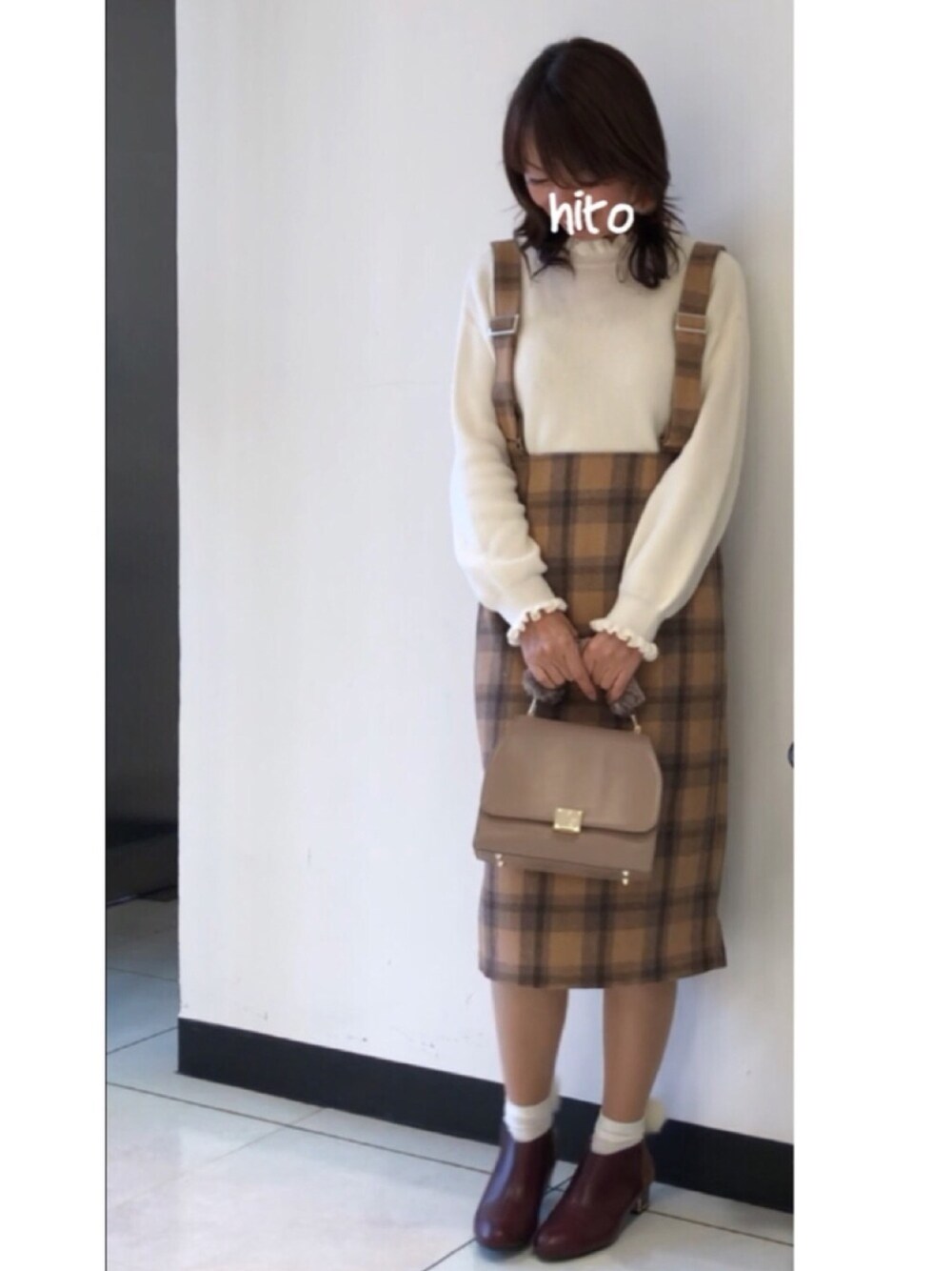 ベージュ系のジャンパースカート、ホワイト系のニット/セーター、レッド系のブーティを着用したレディースの冬コーディネートの1枚目の写真