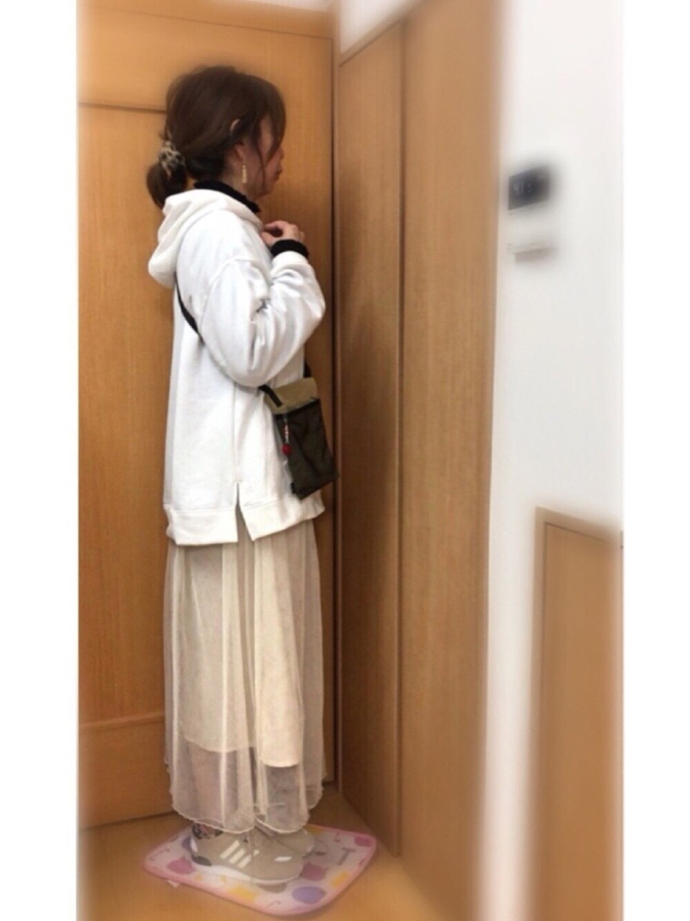 ベージュ系のボディバッグ/ウエストポーチ、ホワイト系のスカート、ベージュ系のスニーカーを着用したレディースの春コーディネートの1枚目の写真