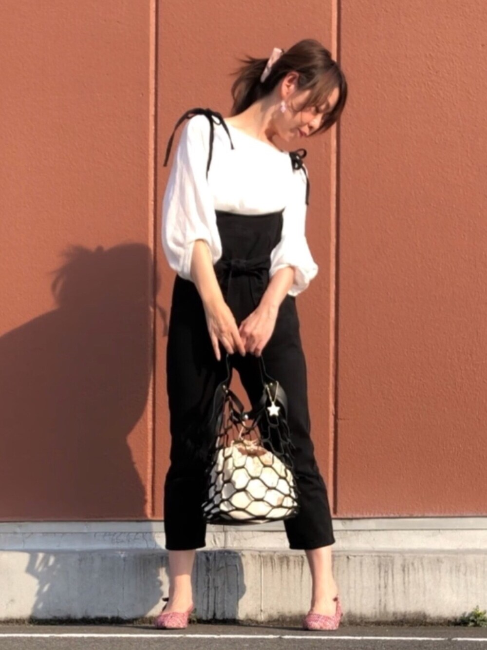 ブラック系のトートバッグ、レッド系のパンプス、ホワイト系のシャツ/ブラウスを着用したレディースの春コーディネートの1枚目の写真