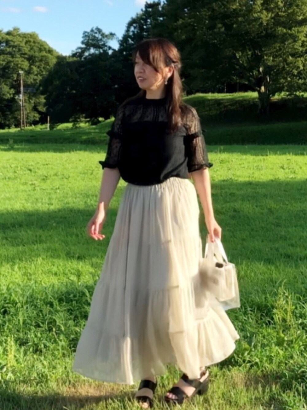 グレー系のスカート、ブラック系のシャツ/ブラウス、ホワイト系のトートバッグを着用したレディースの夏コーディネートの1枚目の写真