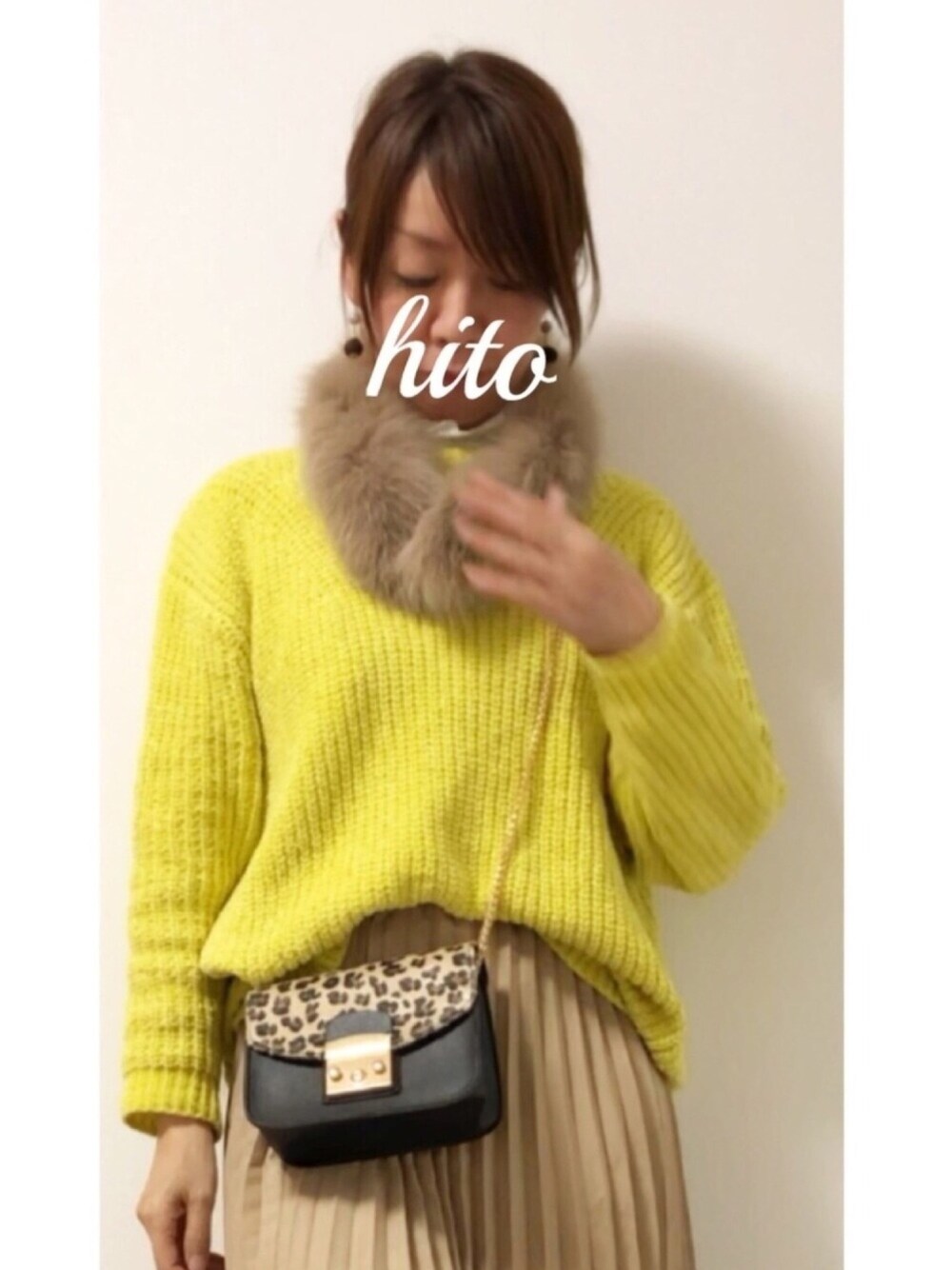 イエロー系のニット/セーター、ベージュ系のスカート、その他のショルダーバッグを着用したレディースの冬コーディネートの1枚目の写真