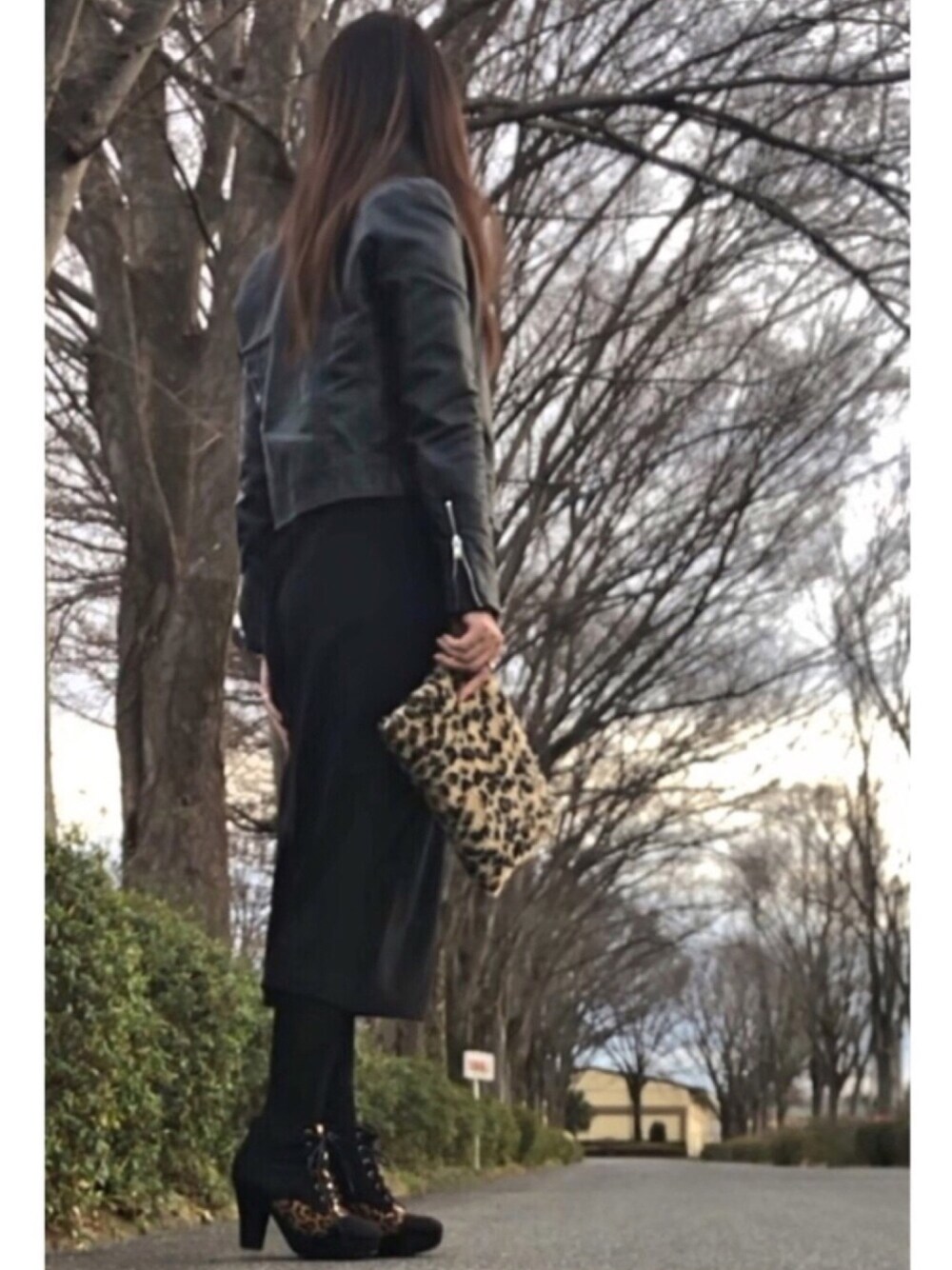 ブラウン系のショルダーバッグ、ブラック系のブーツ、ブラック系のスカートを着用したレディースの冬コーディネートの1枚目の写真