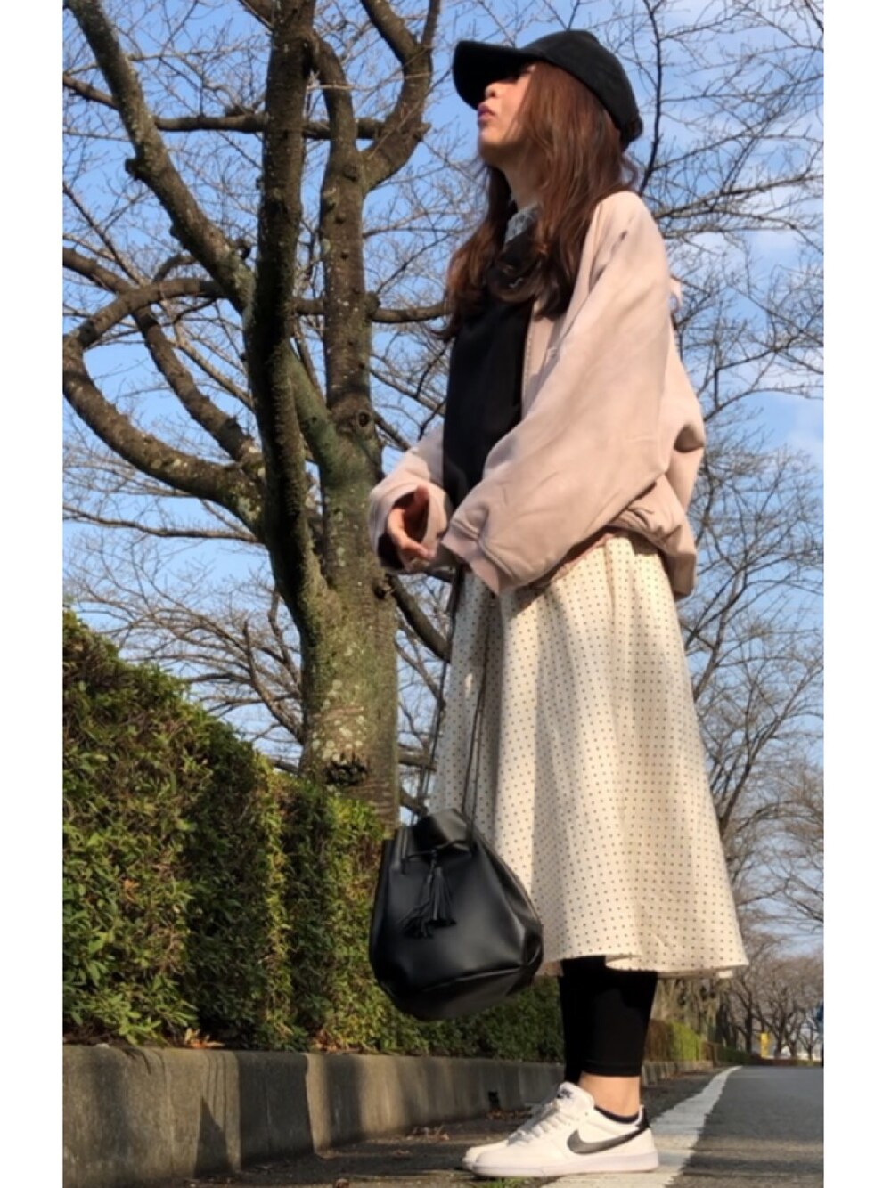 ベージュ系のブルゾン、ホワイト系のスカート、ホワイト系のスニーカーを着用したレディースの春コーディネートの1枚目の写真