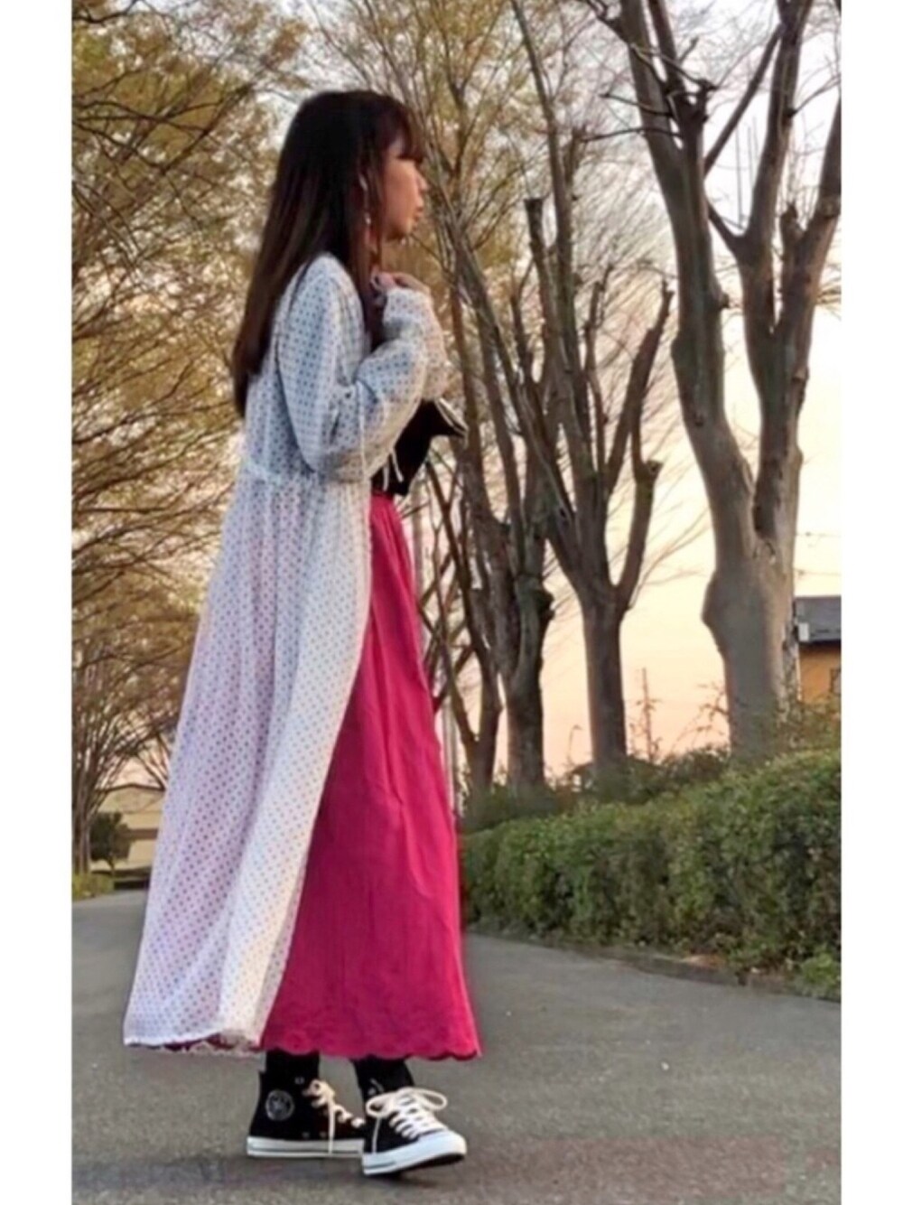 ピンク系のスカート、ホワイト系のシャツワンピース、ブラック系のボディバッグ/ウエストポーチを着用したレディースの春コーディネートの1枚目の写真