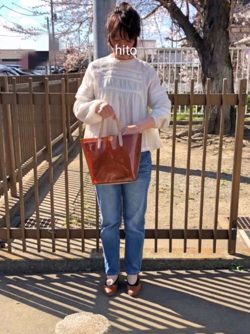 ブラウン系のトートバッグ、ブラウン系のパンプス、ブルー系のデニムパンツを着用したレディースの春コーディネートの1枚目の写真