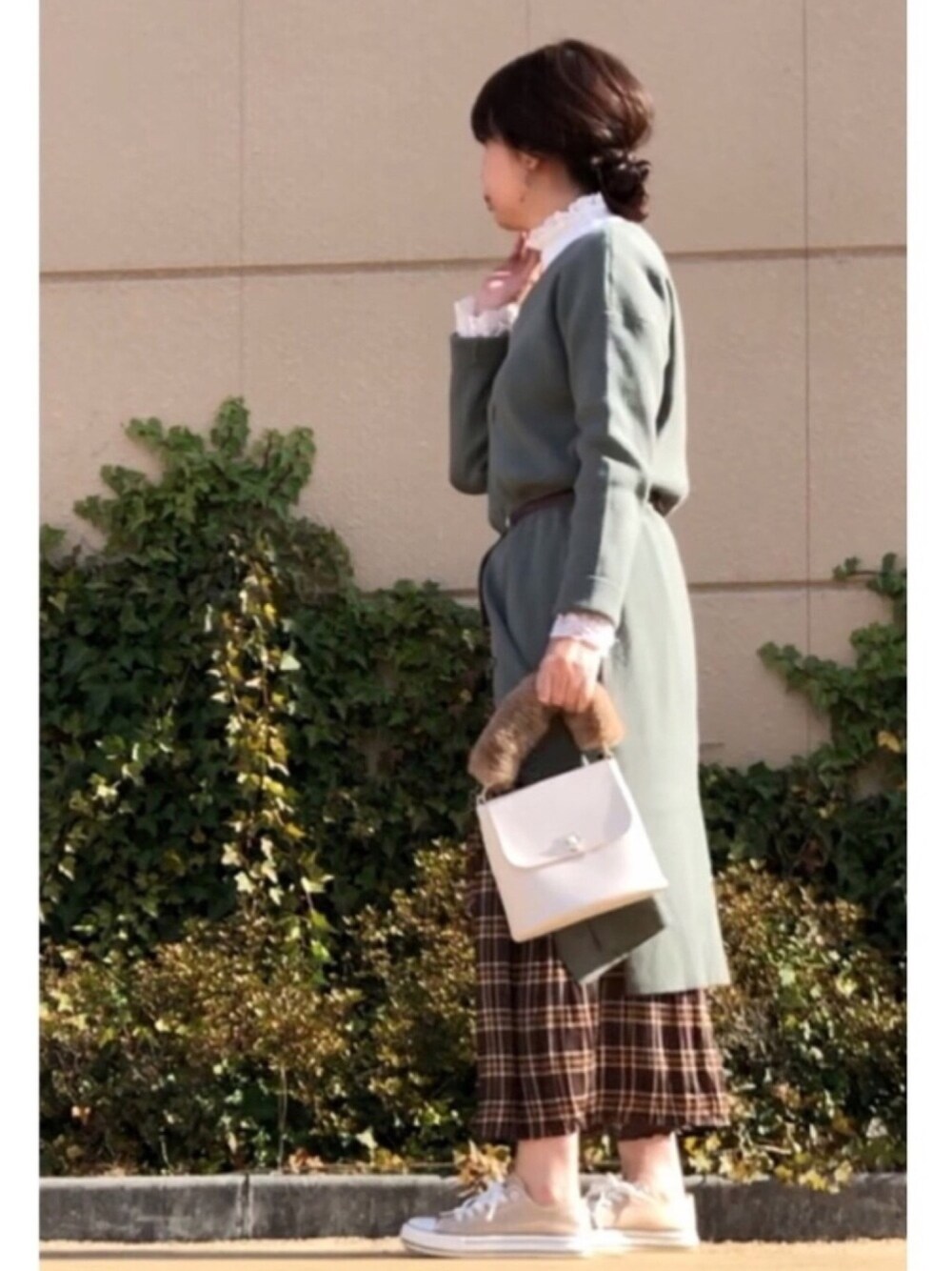 グリーン系のワンピース、ブラウン系のスカート、ベージュ系のスニーカーを着用したレディースの冬コーディネートの1枚目の写真