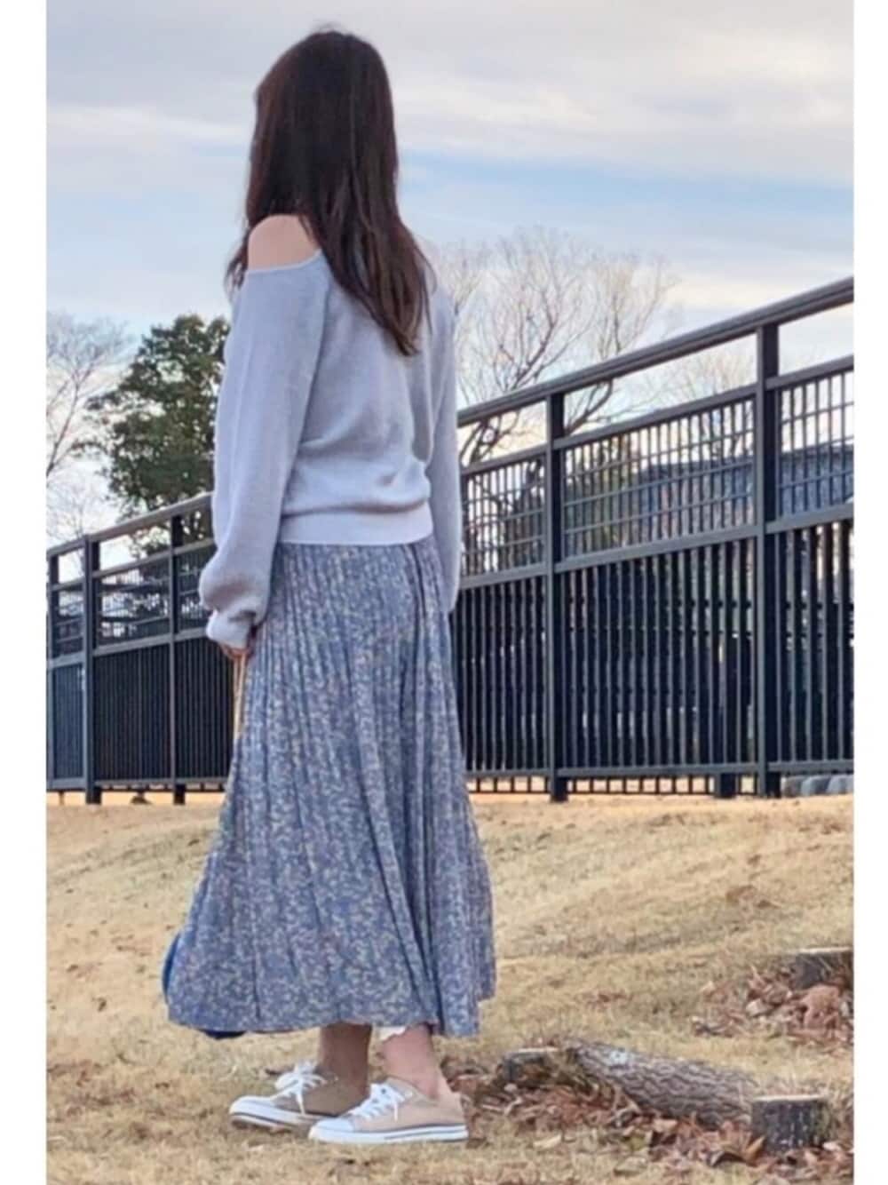 ブルー系のスカート、グレー系のニット/セーター、ブルー系のショルダーバッグを着用したレディースの冬コーディネートの1枚目の写真