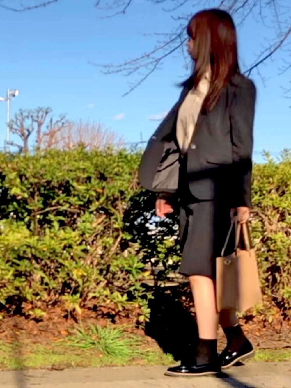 ブラック系のスーツジャケット、ブラック系のスーツスカート、ベージュ系のシャツ/ブラウスを着用したレディースの冬コーディネートの1枚目の写真