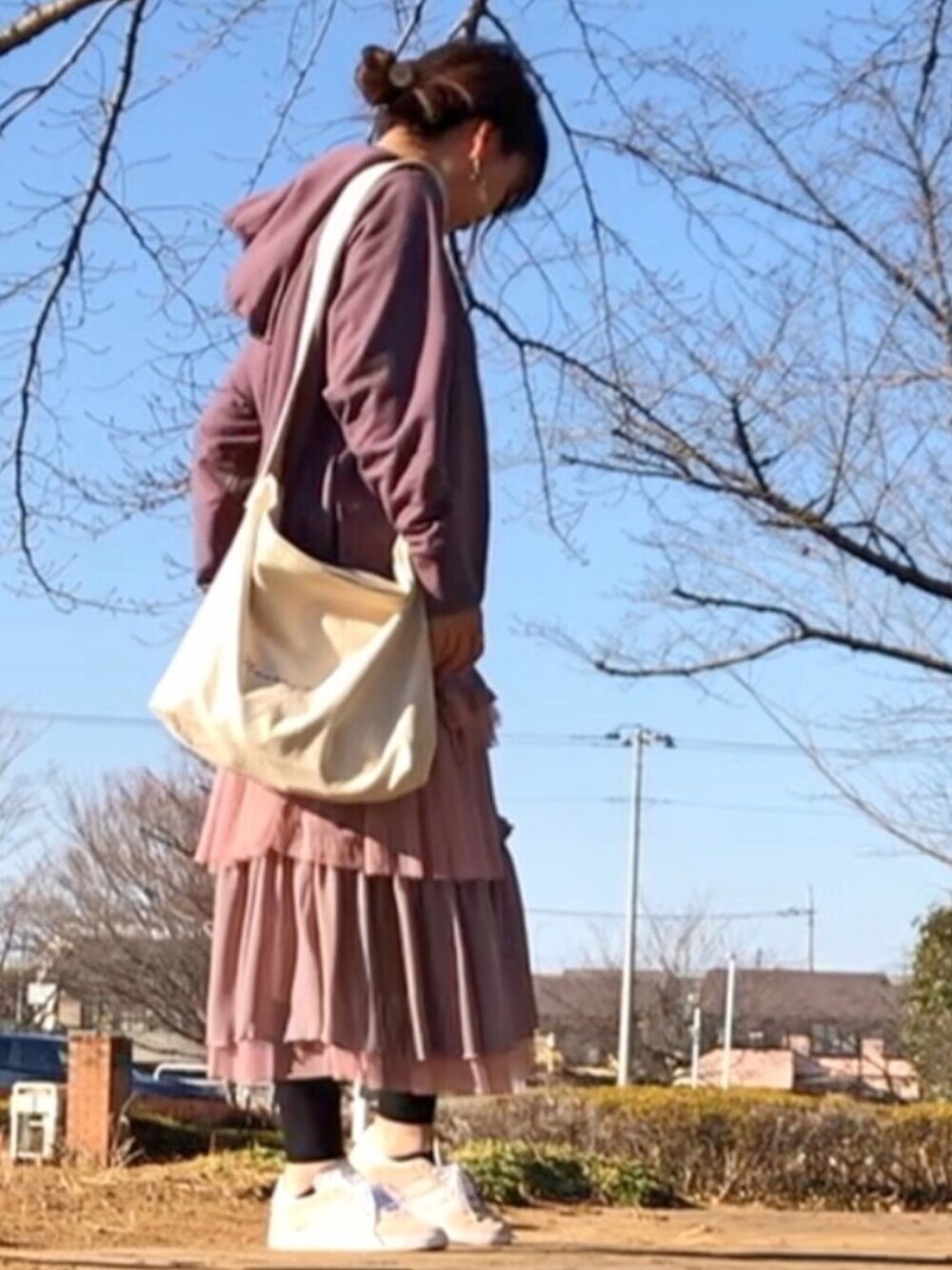 ブラウン系のパーカー、ベージュ系のスニーカー、ベージュ系のショルダーバッグを着用したレディースの冬コーディネートの1枚目の写真