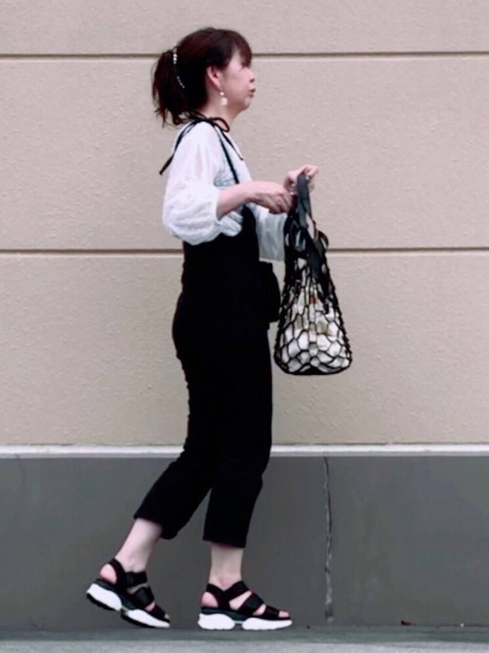 ブラック系のつなぎ/オールインワン、ブラック系のサンダル、ブラック系のトートバッグを着用したレディースの夏コーディネートの1枚目の写真