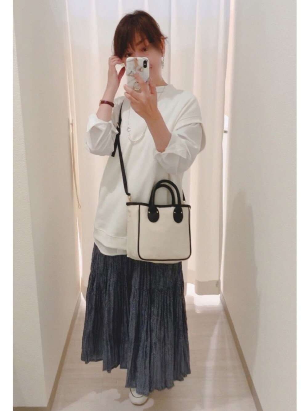 ホワイト系のベスト、ホワイト系のトートバッグ、ホワイト系のスニーカーを着用したレディースの春コーディネートの1枚目の写真
