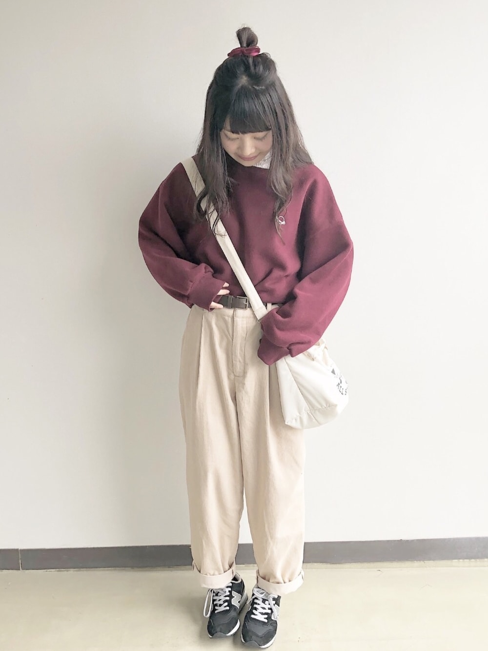レッド系のスウェット、ブルー系のパンツ、ブラック系のスニーカーを着用したレディースの秋コーディネートの1枚目の写真