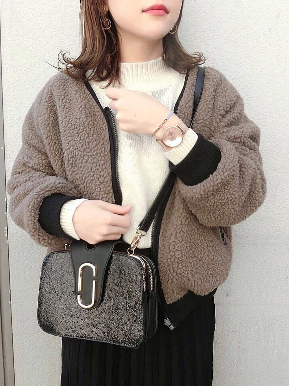 ブラウン系のブルゾン、ブラック系のハンドバッグ、ブラック系のスカートを着用したレディースの冬コーディネートの1枚目の写真