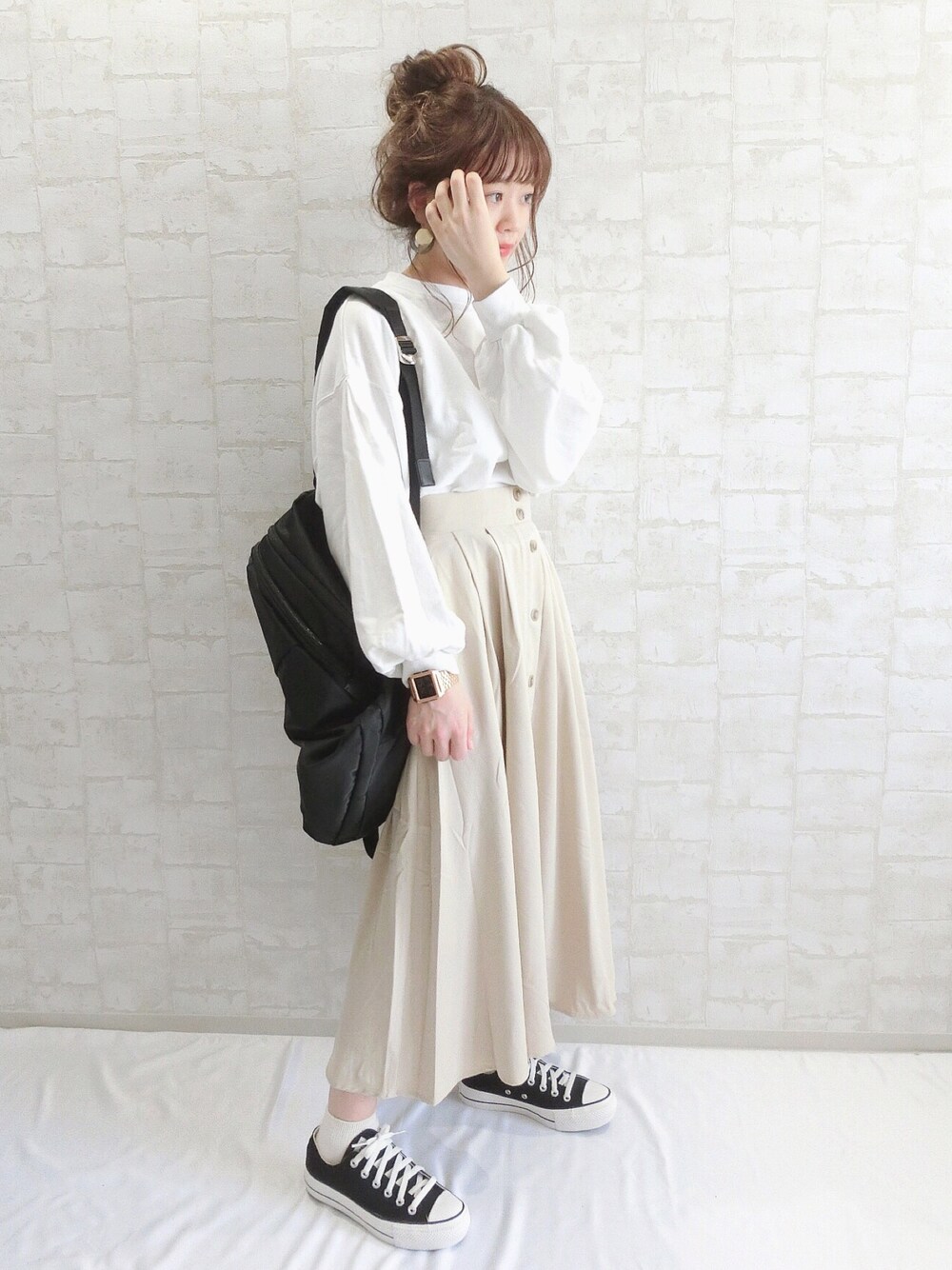 ブラウン系のスカート、ホワイト系のスウェット、ブラック系のバックパック/リュックを着用したレディースの春コーディネートの1枚目の写真