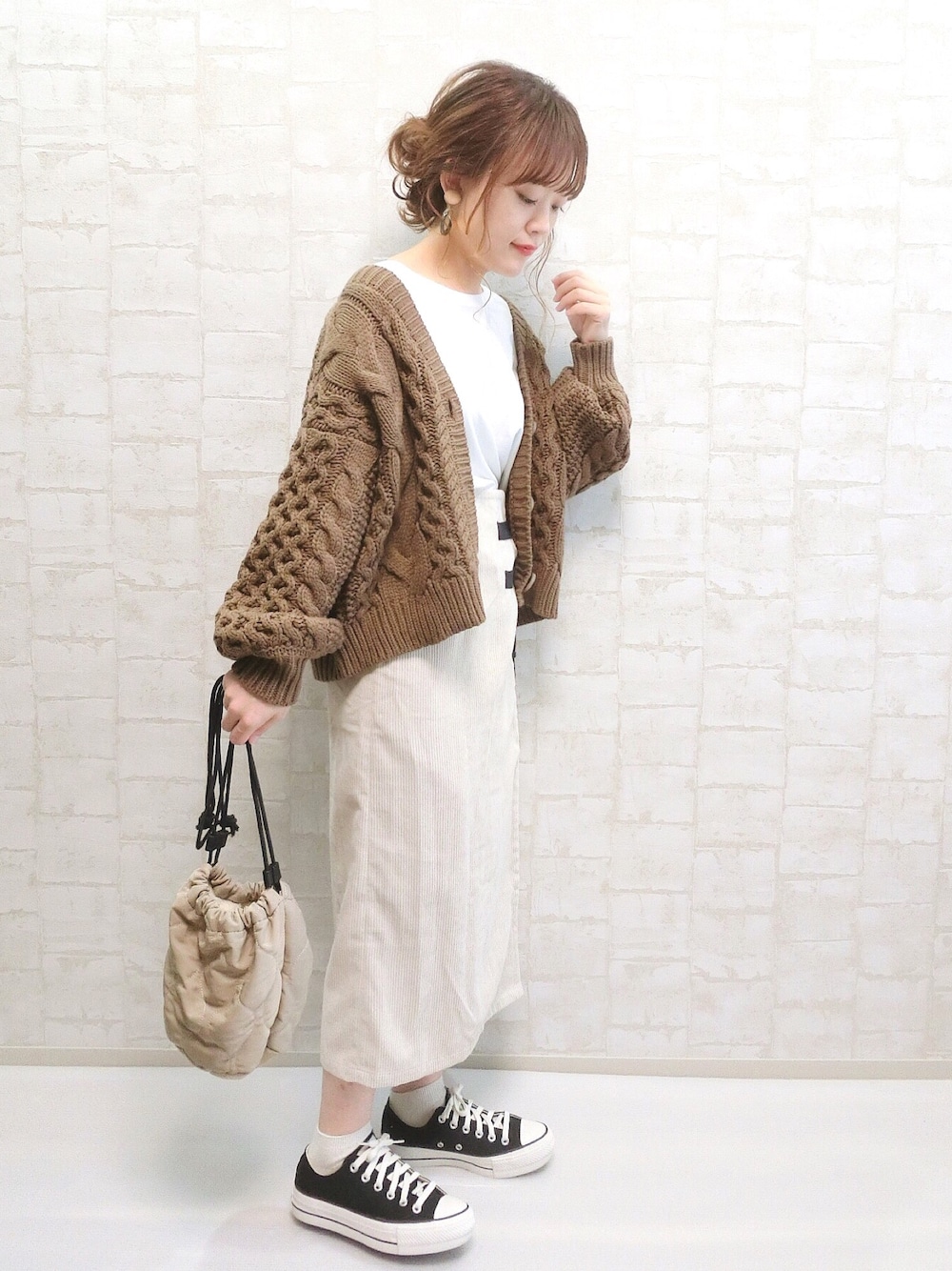 ホワイト系のスカート、ブラウン系のカーディガン/ボレロ、ベージュ系のハンドバッグを着用したレディースの秋コーディネートの1枚目の写真