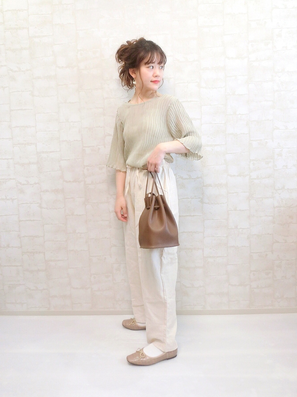 グリーン系のシャツ/ブラウス、ホワイト系のスラックス、ブラウン系のショルダーバッグを着用したレディースの春コーディネートの1枚目の写真