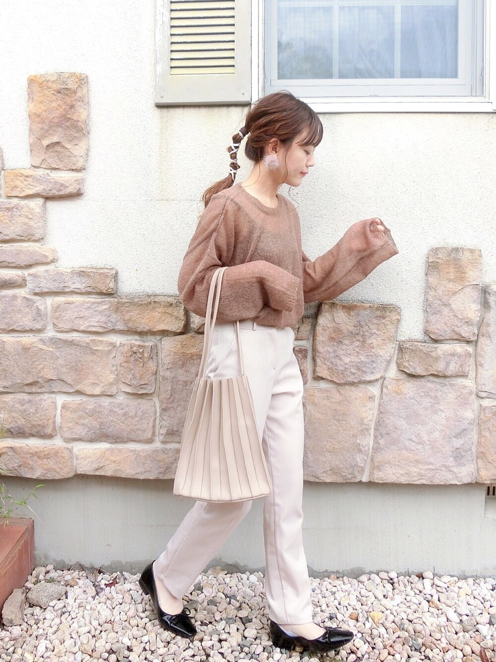 ブラウン系のニット/セーター、ベージュ系のスラックス、ホワイト系のトートバッグを着用したレディースの秋コーディネートの1枚目の写真