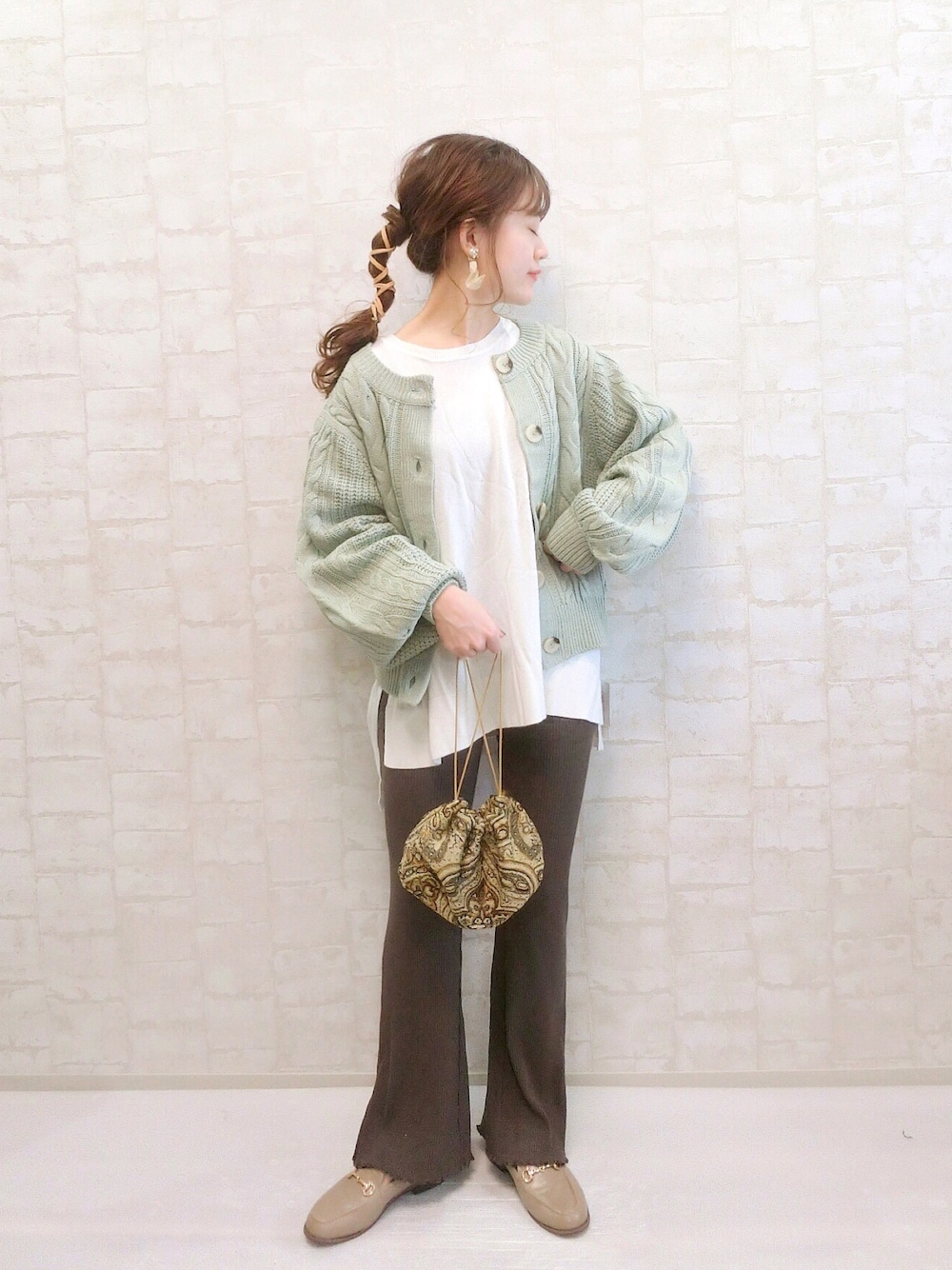 グリーン系のカーディガン/ボレロ、グレー系のスラックス、ベージュ系のショルダーバッグを着用したレディースの秋コーディネートの1枚目の写真