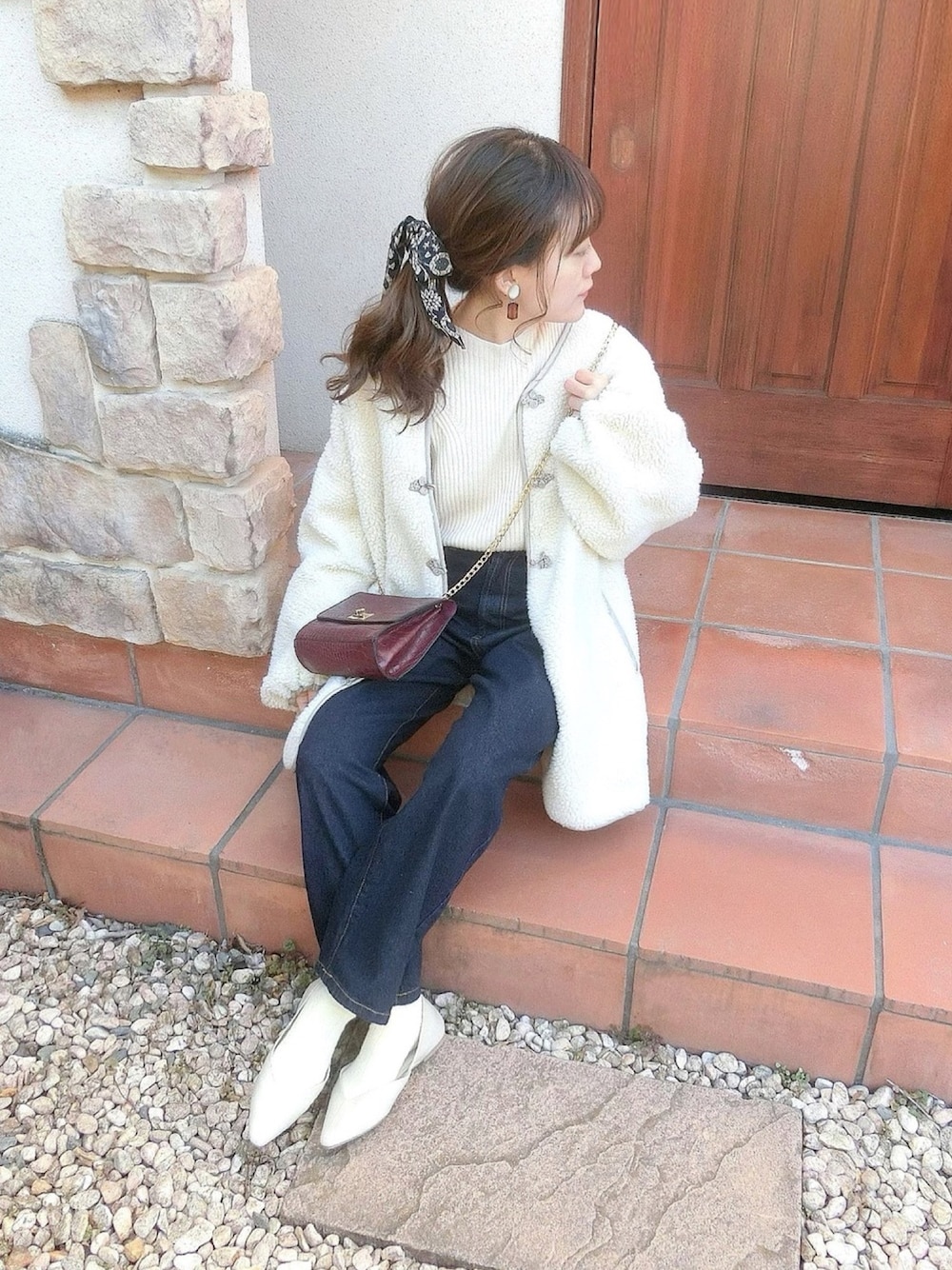 ブルー系のデニムパンツ、レッド系のショルダーバッグ、ホワイト系のその他シューズを着用したレディースの冬コーディネートの1枚目の写真