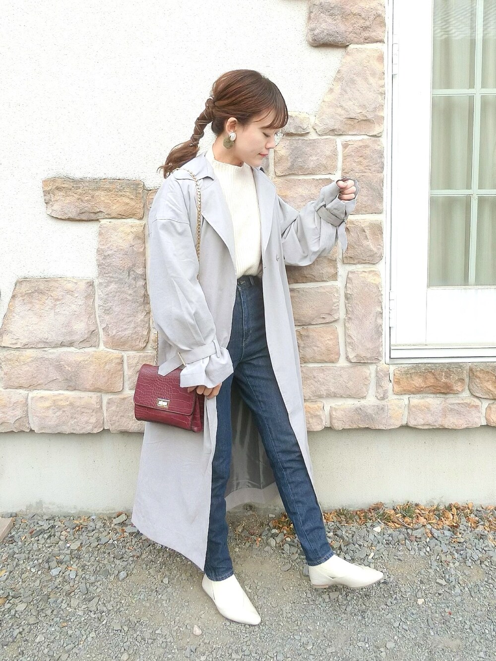 ブラウン系のトレンチコート、ホワイト系のニット/セーター、ブルー系のデニムパンツを着用したレディースの冬コーディネートの1枚目の写真