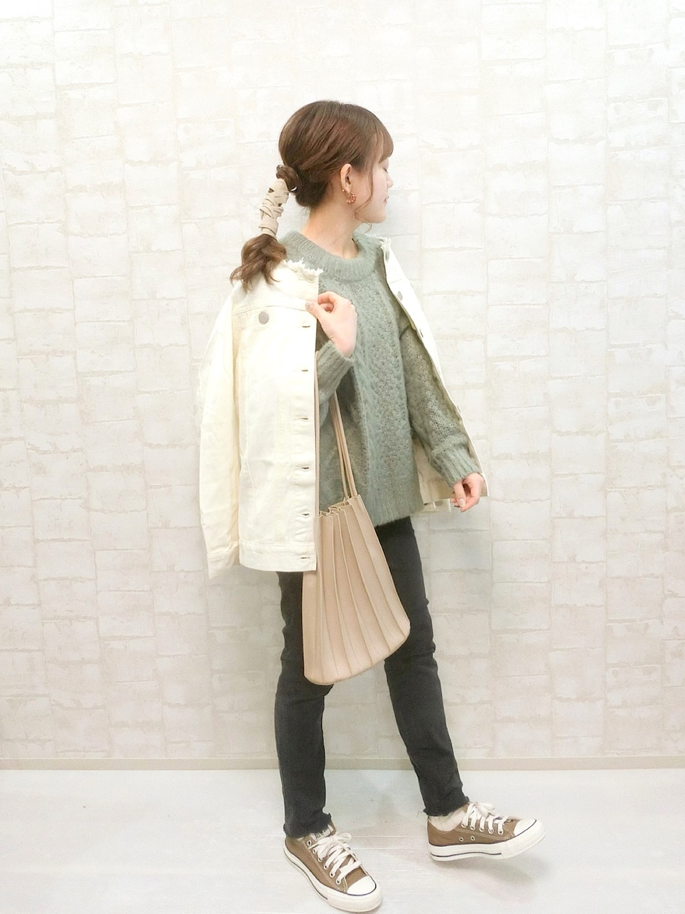 ホワイト系のデニムジャケット、グリーン系のニット/セーター、ホワイト系のトートバッグを着用したレディースの冬コーディネートの1枚目の写真