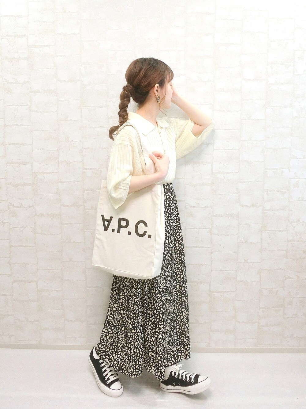 ベージュ系のポロシャツ、ブラック系のスカート、ホワイト系のトートバッグを着用したレディースの春コーディネートの1枚目の写真