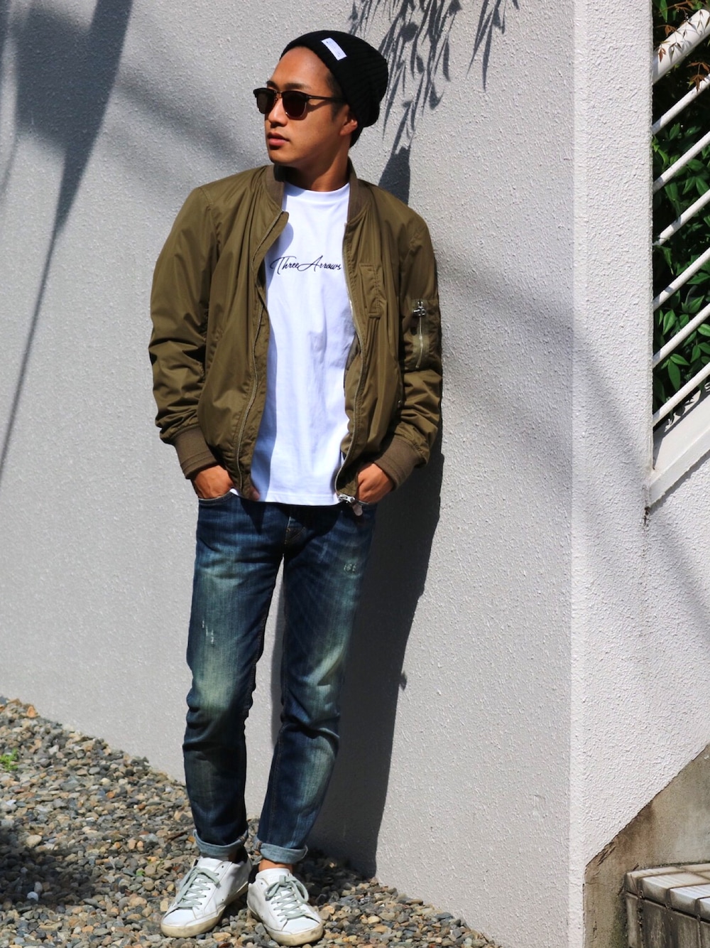 ブラウン系のミリタリージャケット、ホワイト系のTシャツ/カットソー、ブルー系のデニムパンツを着用したメンズの秋コーディネートの1枚目の写真