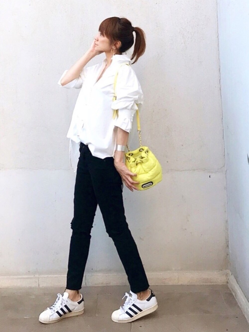 イエロー系のショルダーバッグ、ホワイト系のシャツ/ブラウス、ホワイト系のスニーカーを着用したレディースの夏コーディネートの1枚目の写真