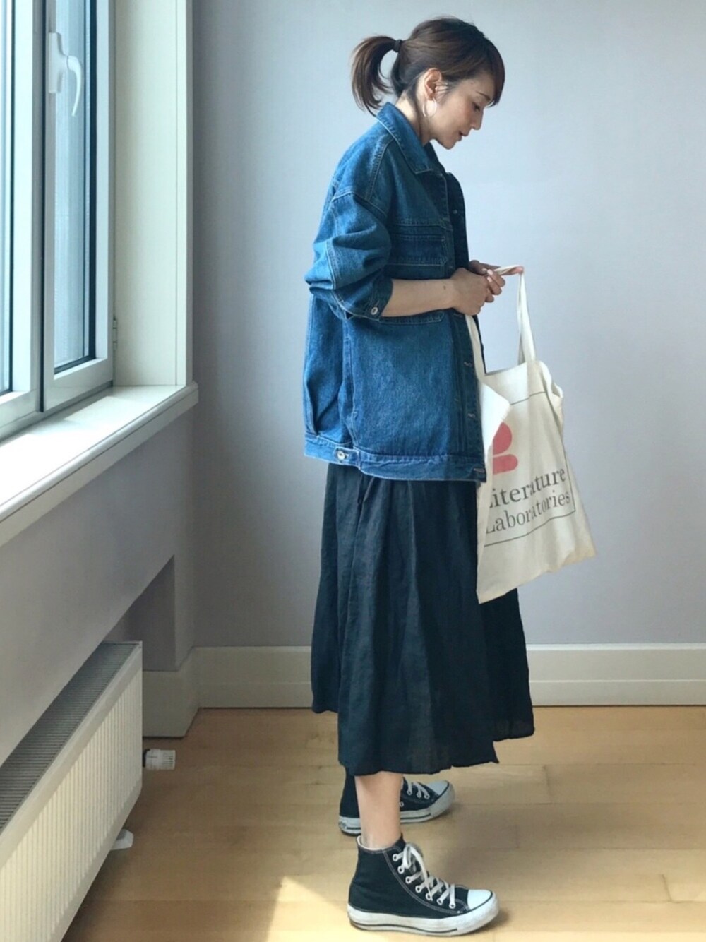 ブルー系のデニムジャケット、ブラック系のスカート、ホワイト系のトートバッグを着用したレディースの春コーディネートの1枚目の写真