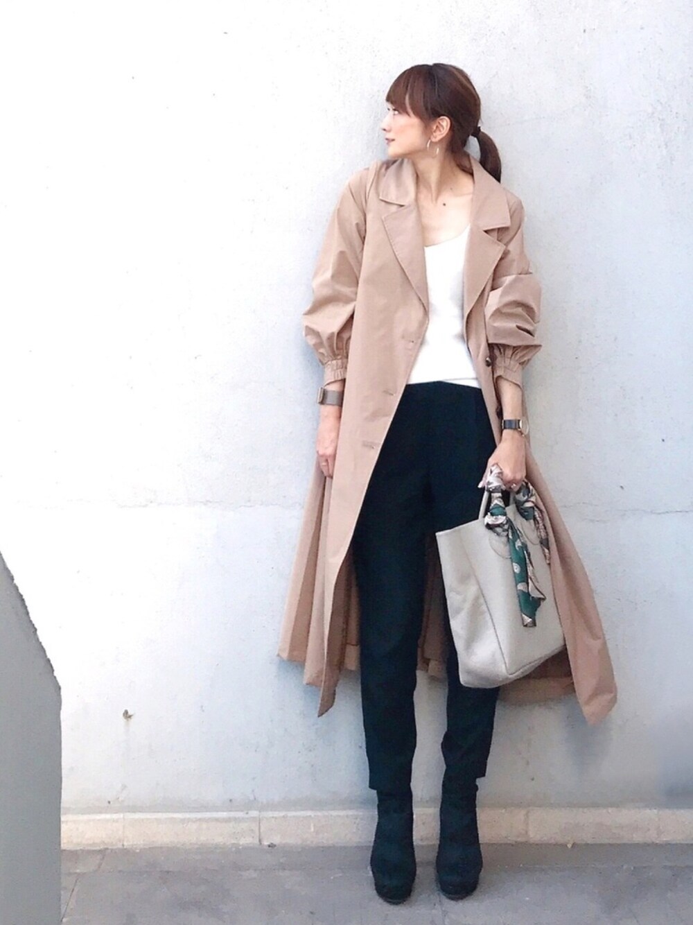 ベージュ系のトレンチコート、ベージュ系のトートバッグ、ホワイト系のキャミソールを着用したレディースの秋コーディネートの1枚目の写真