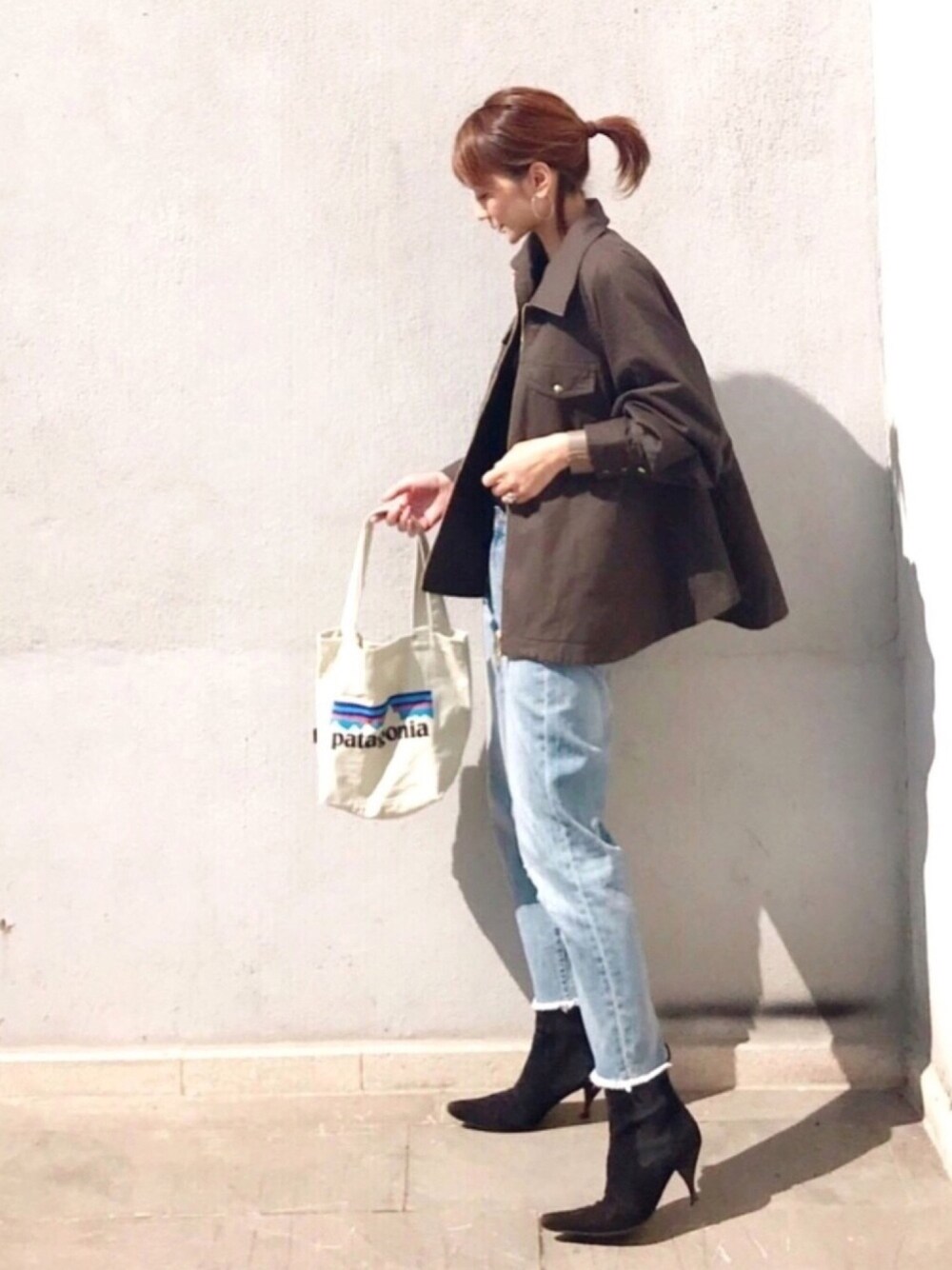 グリーン系のミリタリージャケット、ホワイト系のトートバッグ、ブルー系のデニムパンツを着用したレディースの秋コーディネートの1枚目の写真