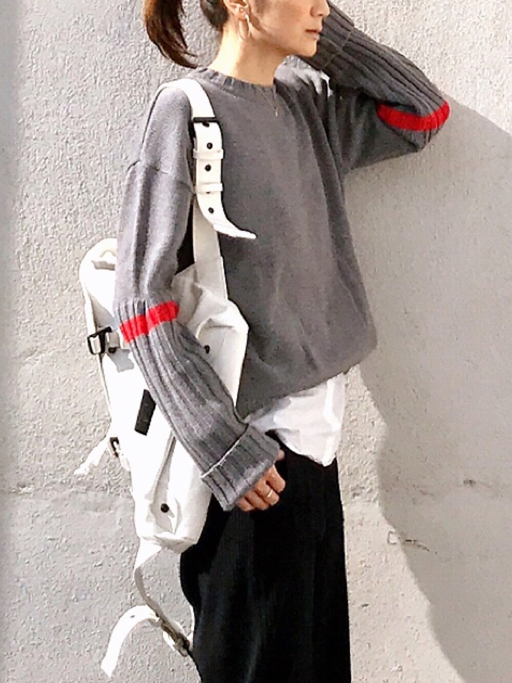 グレー系のニット/セーター、ブラック系のスカート、ホワイト系のバックパック/リュックを着用したレディースの秋コーディネートの1枚目の写真