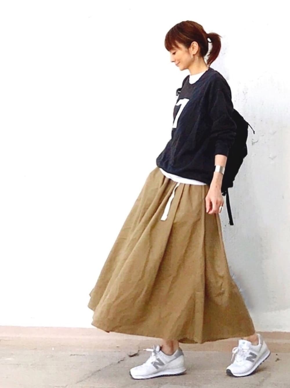 ブラック系のスウェット、ベージュ系のスカート、ホワイト系のスニーカーを着用したレディースの春コーディネートの1枚目の写真