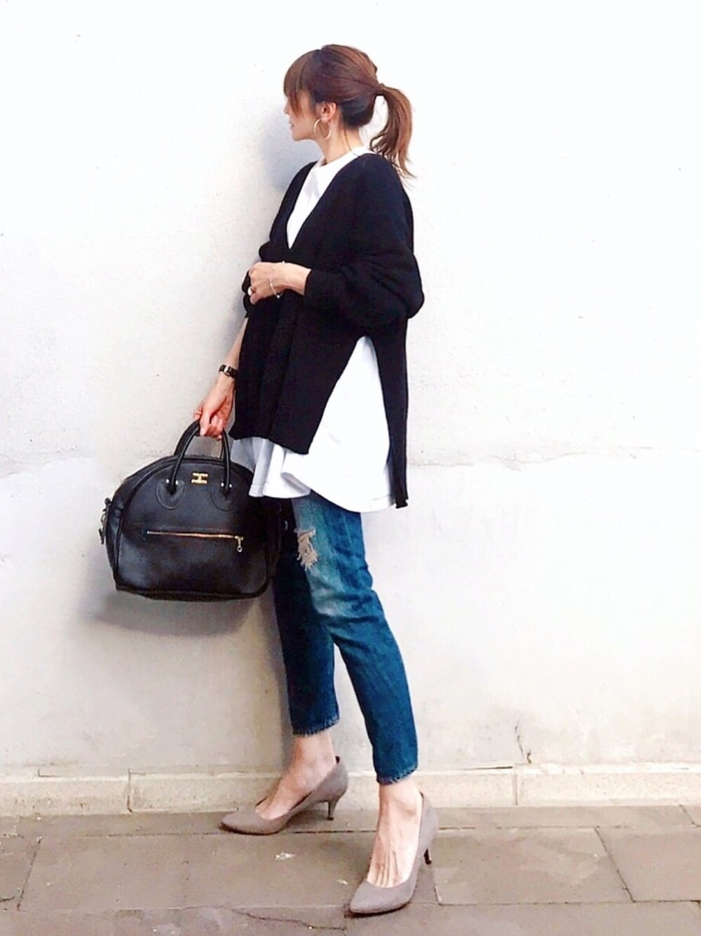 ブラック系のショルダーバッグ、ブラック系のニット/セーター、ホワイト系のスウェットを着用したレディースの春コーディネートの1枚目の写真