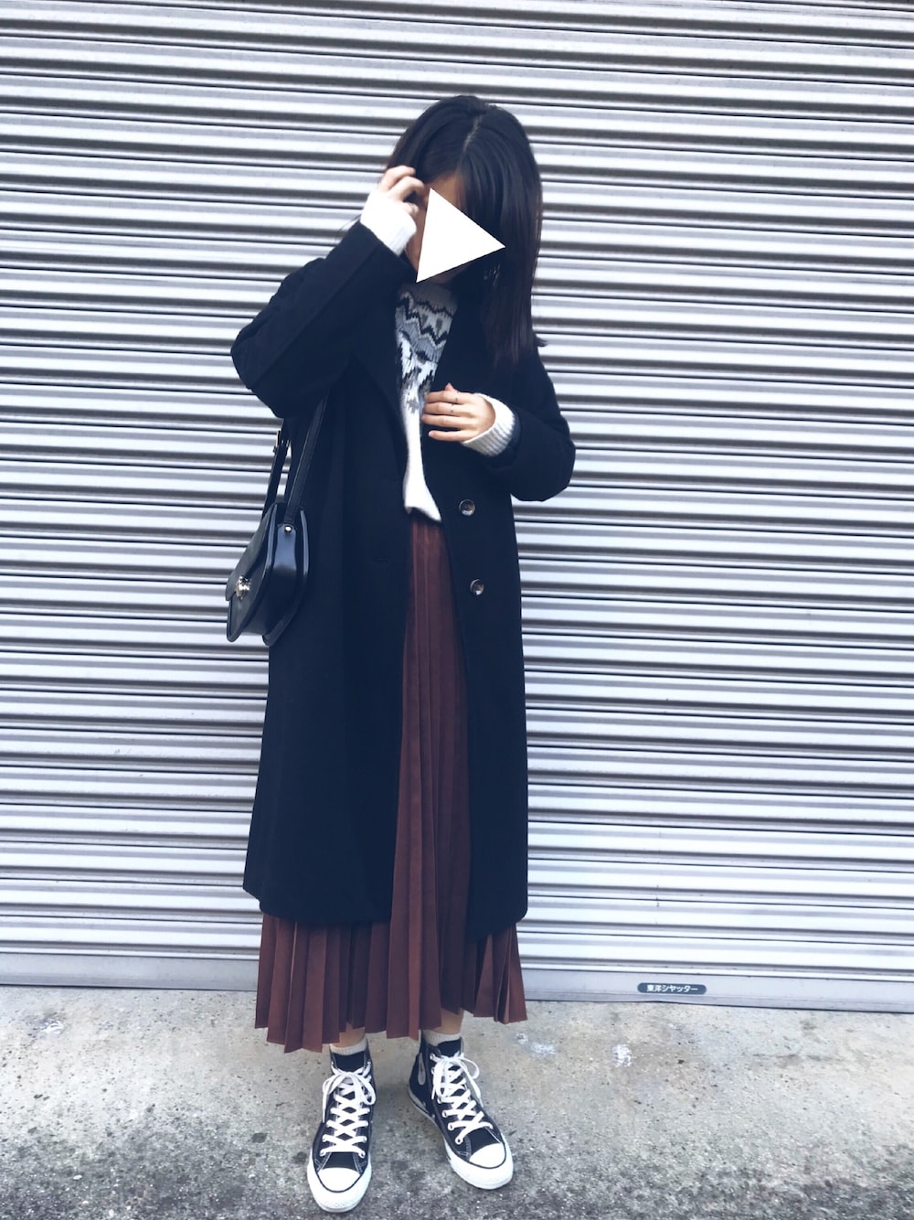 ブラウン系のスカート、ホワイト系のニット/セーター、ブラック系のチェスターコートを着用したレディースの冬コーディネートの1枚目の写真