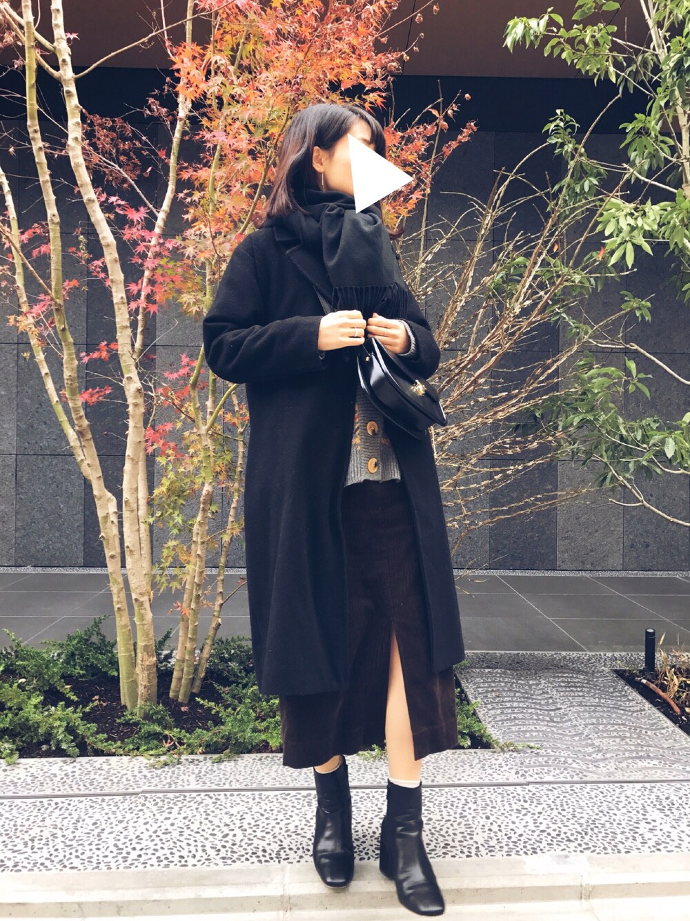 ブラウン系のスカート、ブラック系のブーツ、ブラック系のショルダーバッグを着用したレディースの冬コーディネートの1枚目の写真