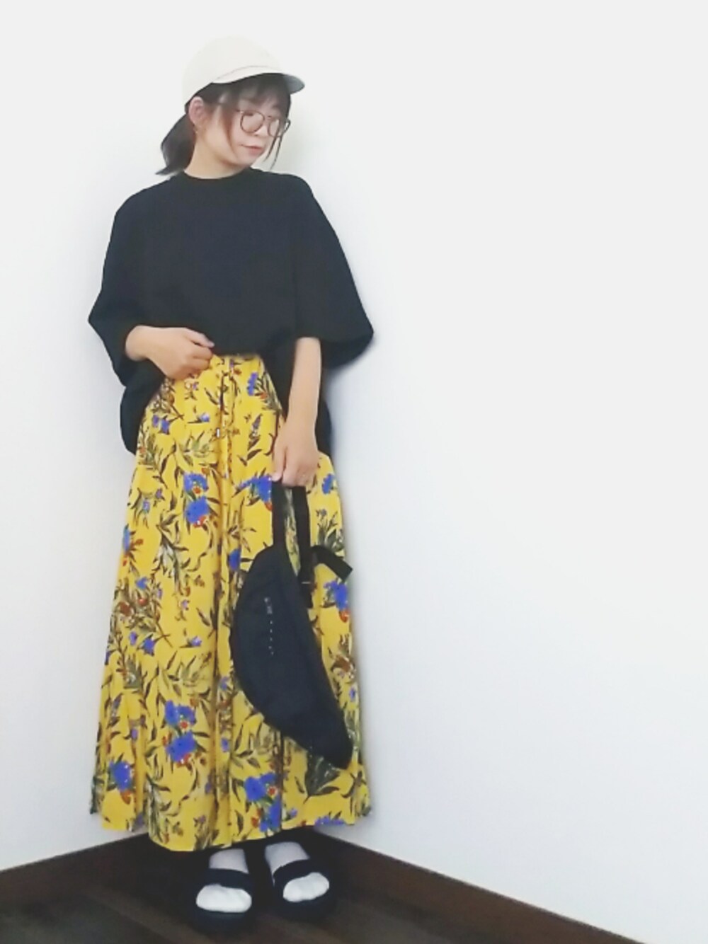 イエロー系のスカート、ブラック系のTシャツ/カットソー、ブラック系のサンダルを着用したレディースの春コーディネートの1枚目の写真
