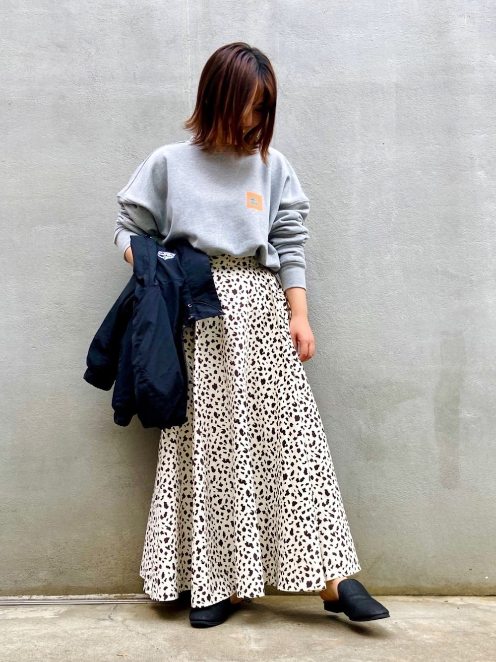 グレー系のスウェット、ブラック系のマウンテンパーカーを着用したレディースの秋コーディネートの1枚目の写真