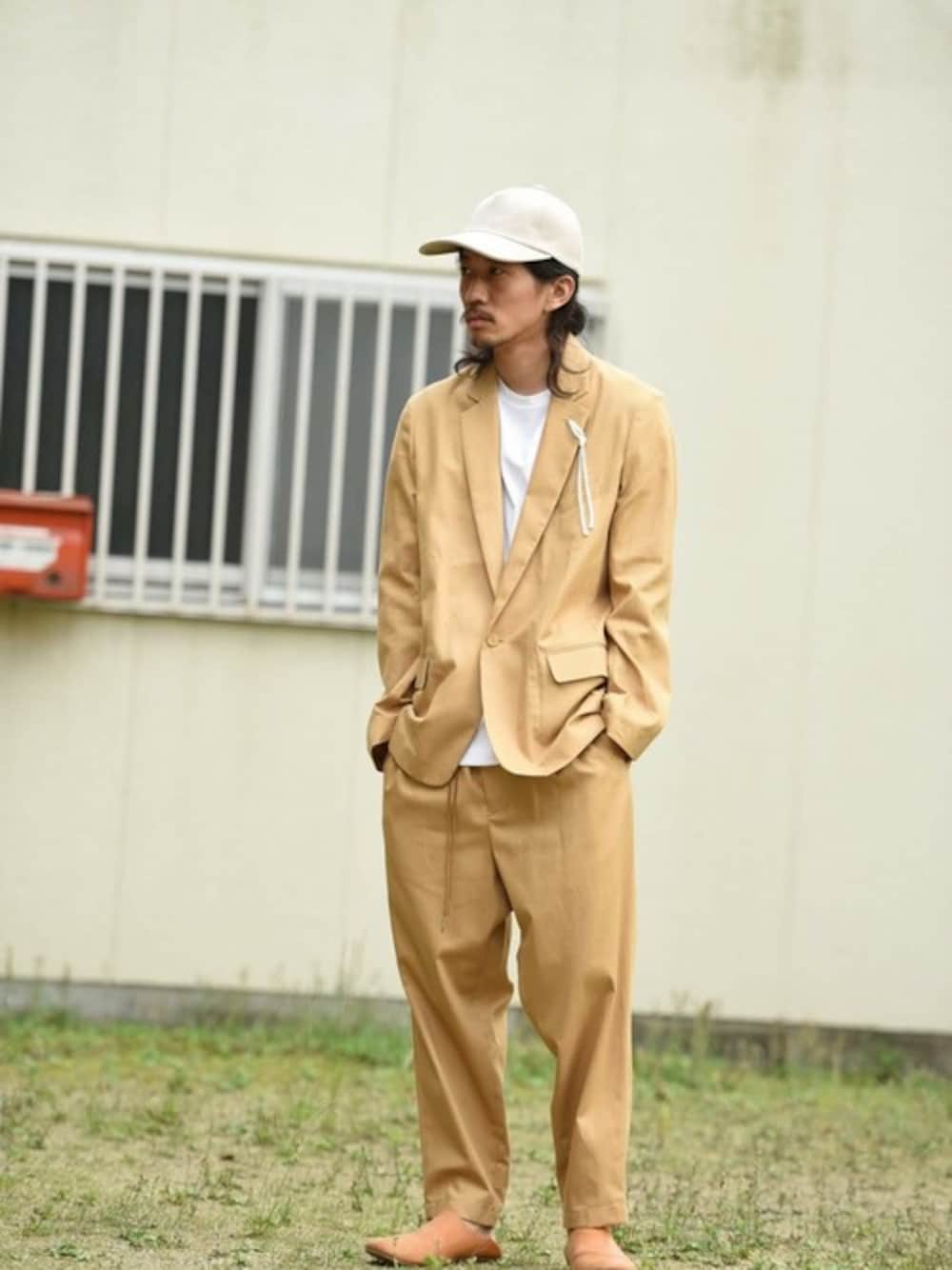 ベージュ系のスラックス、ベージュ系のテーラードジャケット、ベージュ系のキャップを着用したメンズの夏コーディネートの1枚目の写真