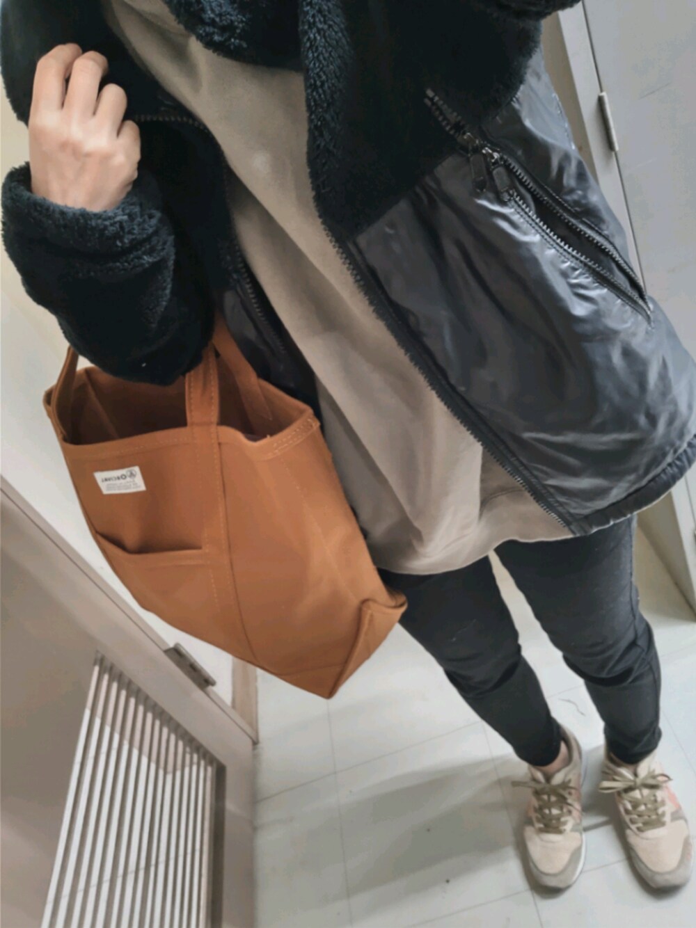 ブラウン系のトートバッグ、ベージュ系のスニーカー、ブラック系のその他パンツを着用したレディースの秋コーディネートの1枚目の写真