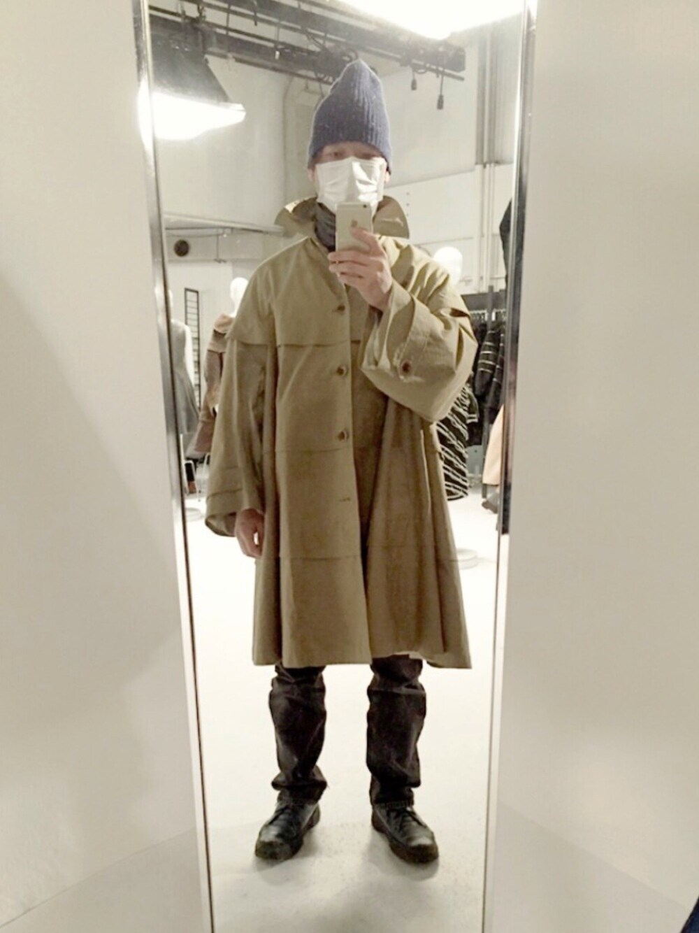 ブラック系のデニムパンツ、ブルー系のブーツ、ブラウン系のステンカラーコートを着用したメンズの春コーディネートの1枚目の写真