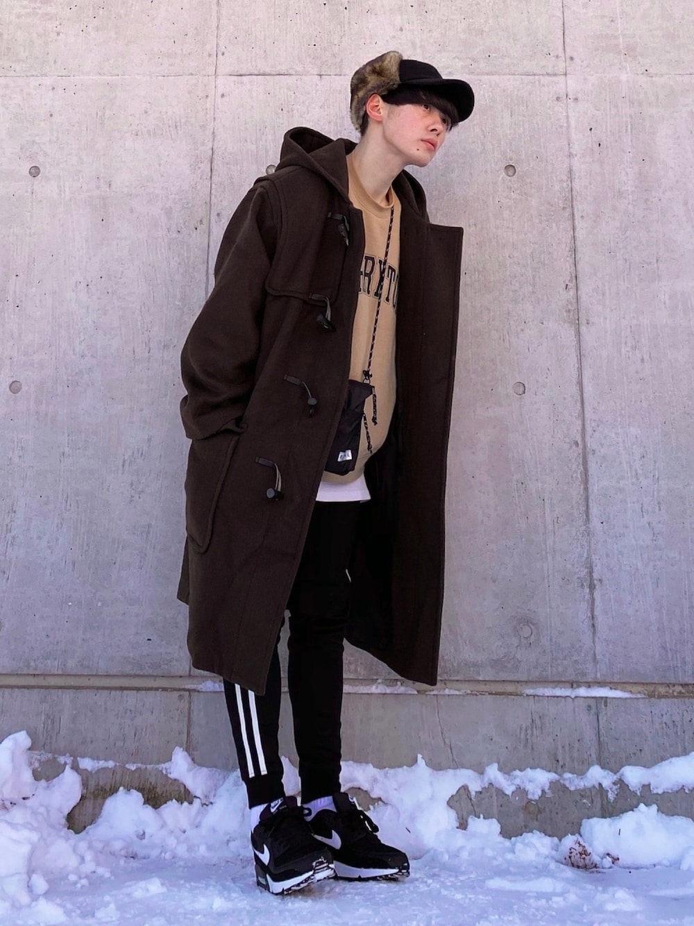 ブラウン系のダッフルコート、ベージュ系のスウェット、ブラック系のショルダーバッグを着用したメンズの冬コーディネートの1枚目の写真