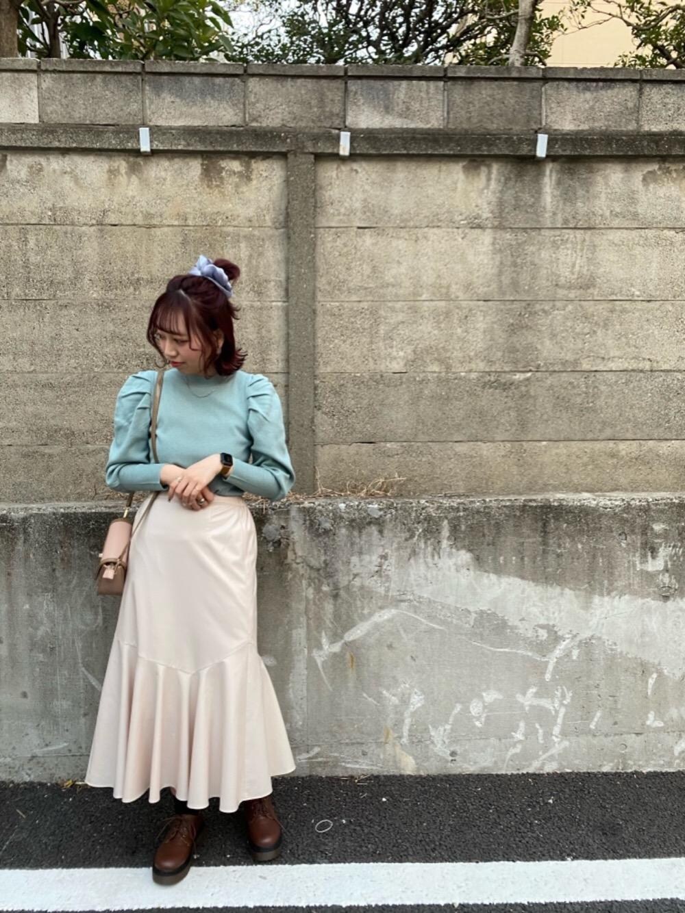 ブラウン系のブーツ、グリーン系のニット/セーター、ベージュ系のスカートを着用したレディースの冬コーディネートの1枚目の写真