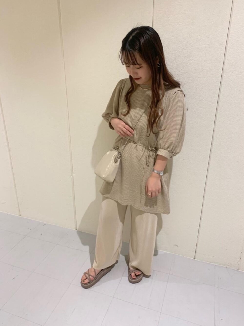 ゴールド系のショルダーバッグ、ベージュ系のサンダル、ホワイト系のその他パンツを着用したレディースの春コーディネートの1枚目の写真